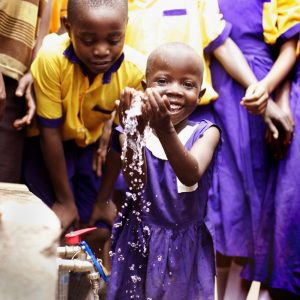 Young girl splashing water from a rainwater collection system
