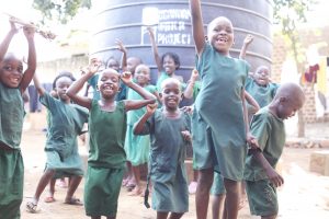 Students jumping in front of a rainwater collection system
