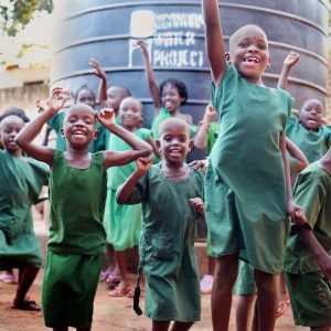 Students jumping in front of a rainwater collection system tank.