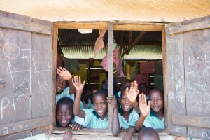 Ugandan children waving from schoolhouse window